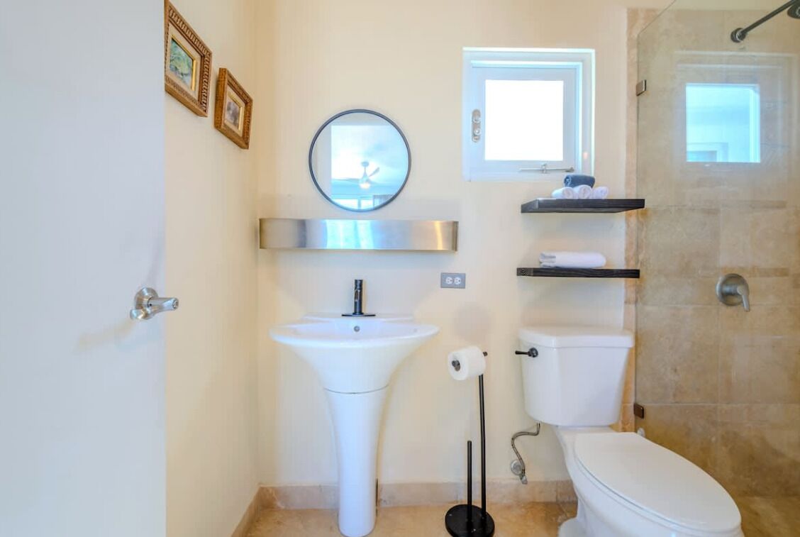 A bathroom with a white sink, toilet, and a shower area.