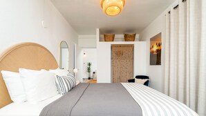 A bedroom with a large bed, a desk, a chair, a mirror, and a view of the outside. - Rincon Surf Club - Beachside & Pool (Rincón)