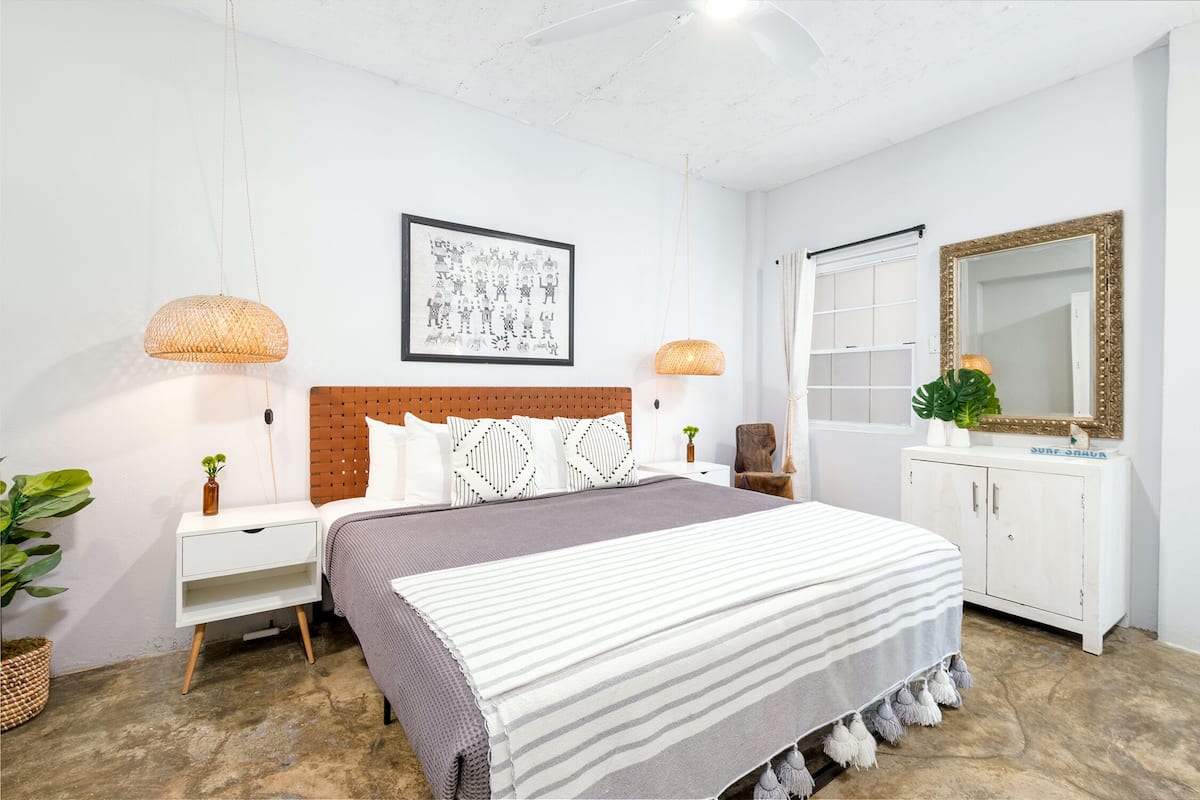 A bedroom with a bed, nightstands, a large mirror, and a framed picture on the wall.