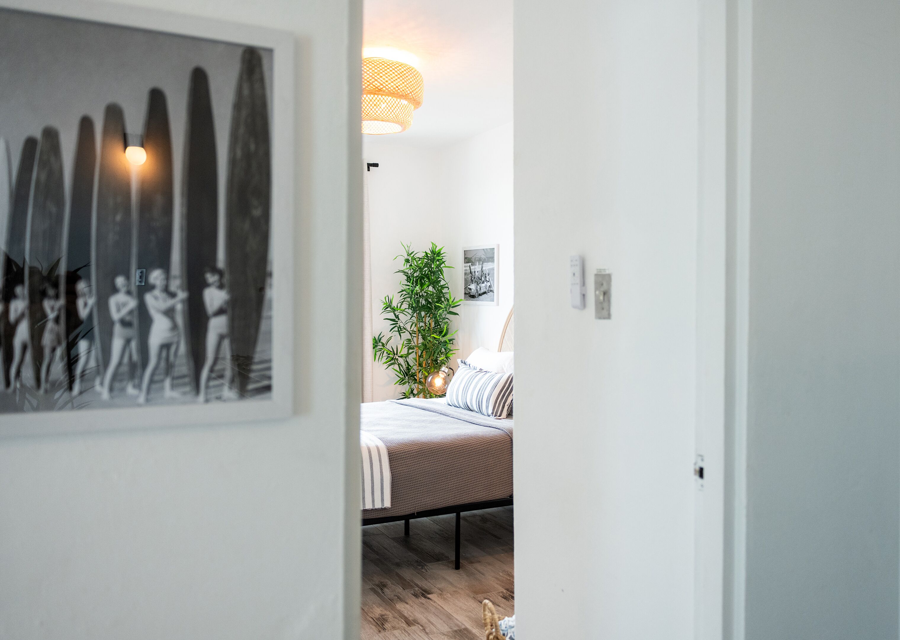 A bedroom with a bed, a potted plant, and a wall-mounted light fixture.