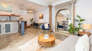 A modern kitchen with a dining area, a large mirror, and a cozy seating area with a round wooden table. - Rincon Surf Club - Beachside & Pool (Rincón)