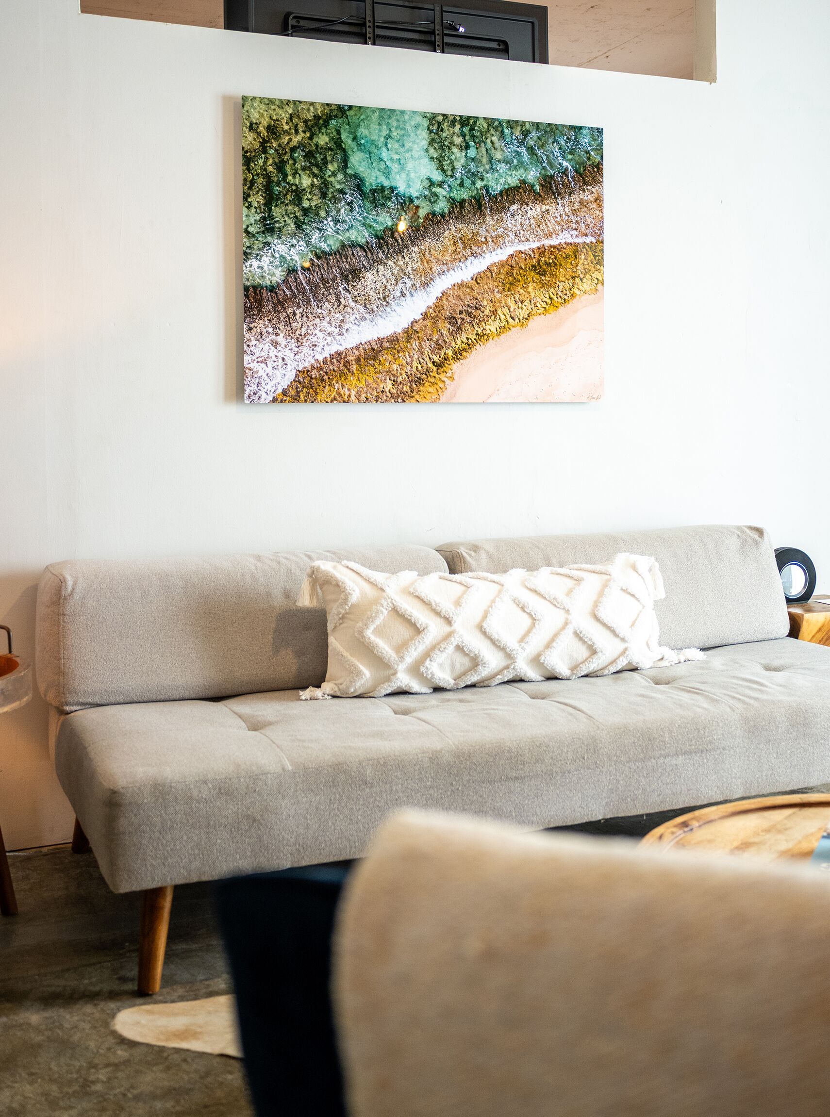 Una sala de estar moderna con un sofá gris, un cojín blanco y una obra de arte colgada en la pared.