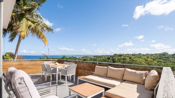 A rooftop terrace with a sofa, chairs, a table, and a view of the ocean. - Rincon Surf Club - Beachside & Pool (Rincón)