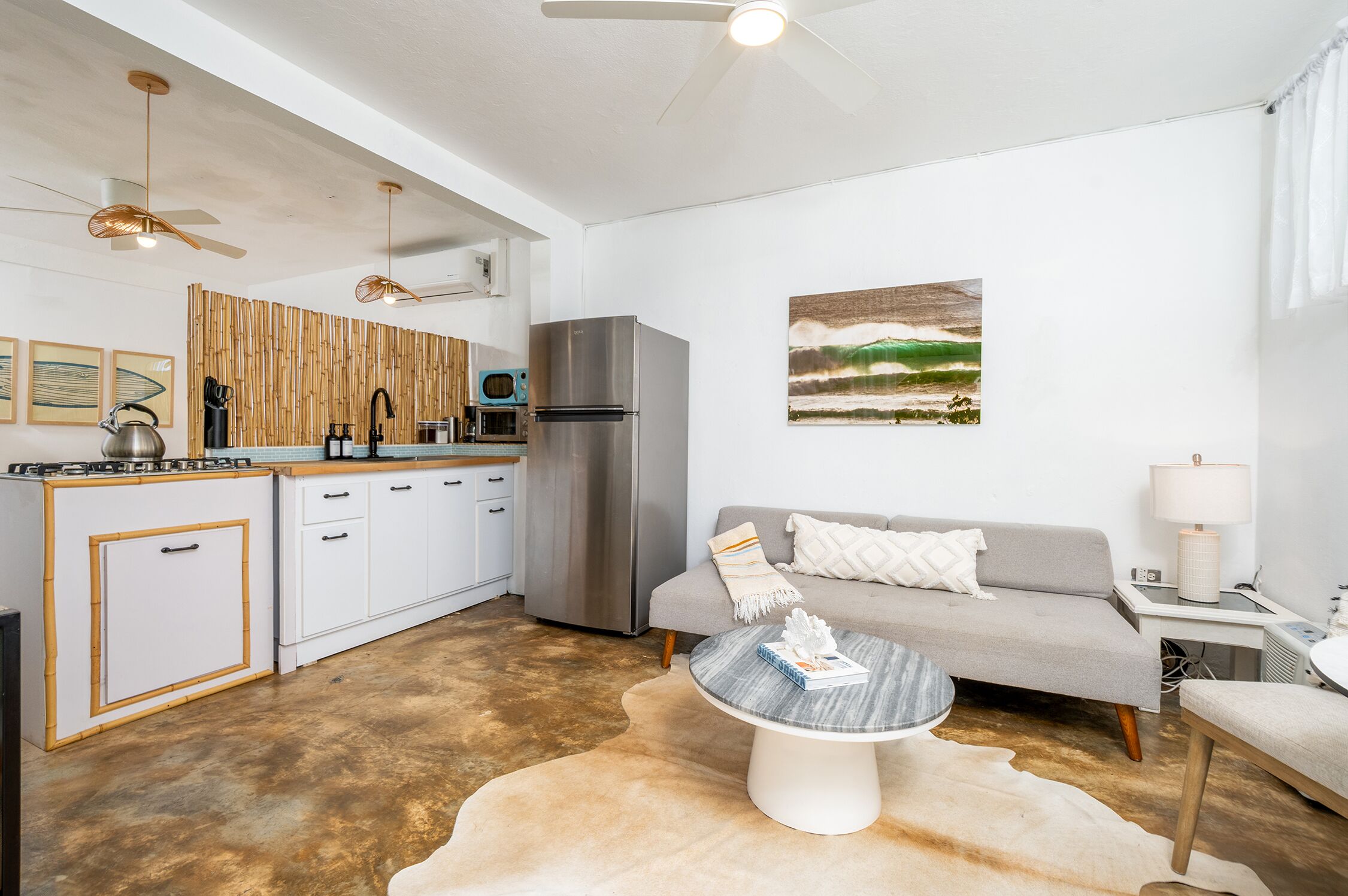 A modern kitchen with white cabinets, a stainless steel refrigerator, and a bamboo wall.