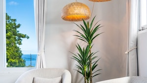 A room with a view of the sea, a round armchair, a sofa, and two hanging wicker lamps. - Rincon Surf Club - Beachside & Pool (Rincón)