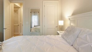 A hotel room with a bed, a nightstand, a mirror, and a door leading to a closet. - Poolside Boutique Guest House | Fort Lauderdale (Fort Lauderdale)