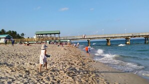 A beach with a pier, sandy shore, and people. - Poolside Boutique Guest House | Fort Lauderdale (Fort Lauderdale)