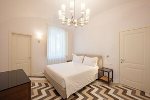 Une chambre à coucher avec un lit, un bureau, une table de chevet, un lustre et un sol à motifs.