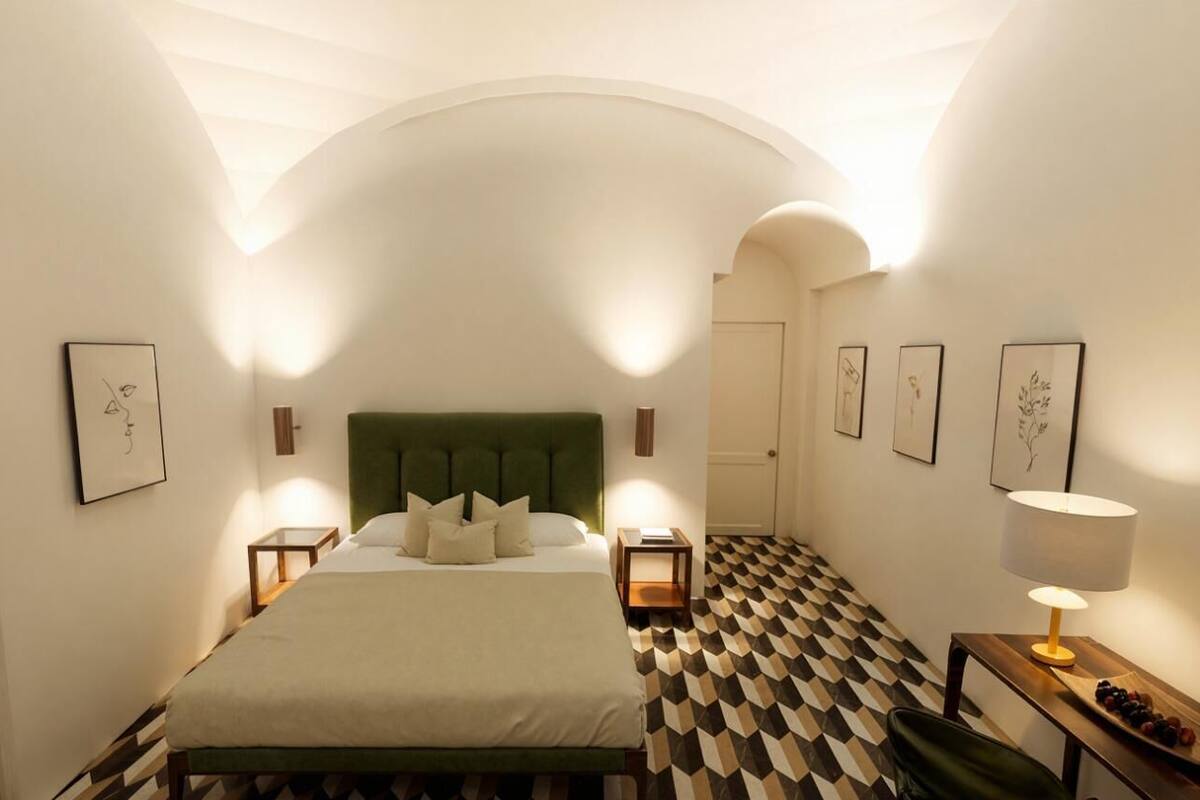 Una habitació d'hotel amb un llit, taulells laterals, una làmpada i un terra de quadres.