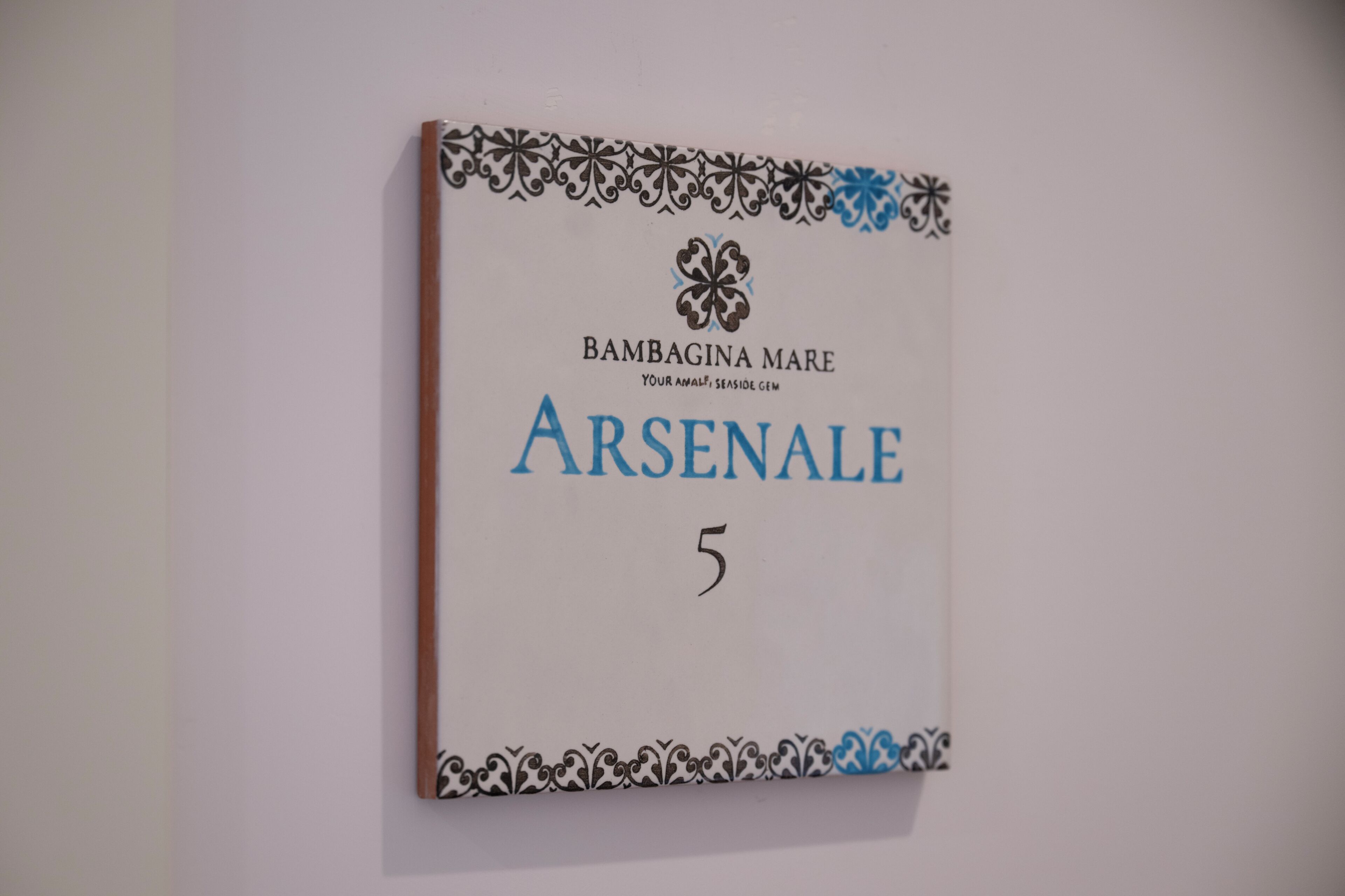 A book titled 'Bambagina Mare' with the subtitle 'Your Ankle, Seaside Gem' and the word 'ARSENALE' in large letters.