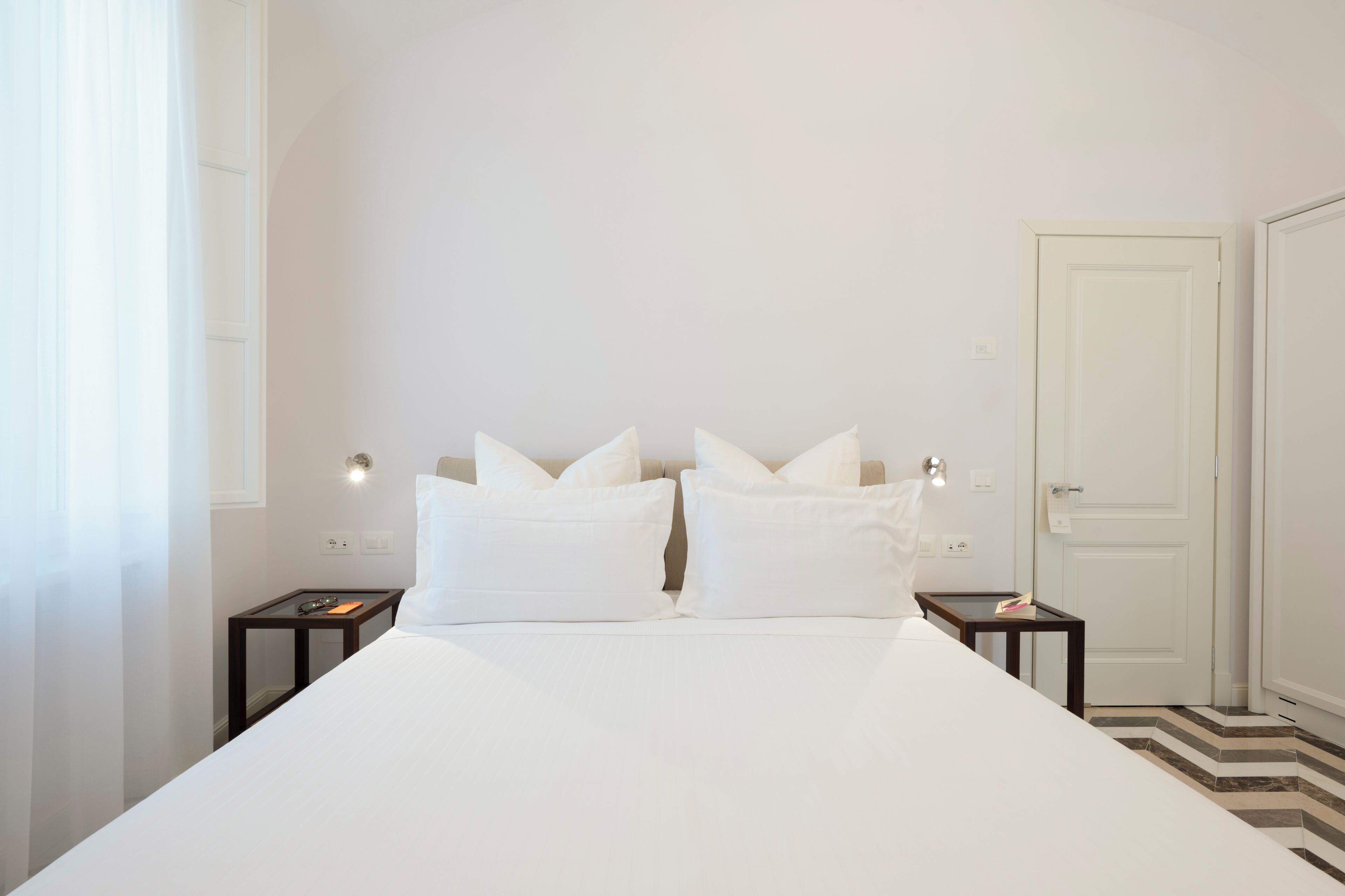 Una camera da letto con un letto grande, due comodini, una porta e una finestra con tende.