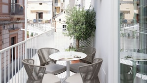A balcony with a round table and chairs, a potted plant, and a view of buildings and hills. - Bambagina Mare (Amalfi)