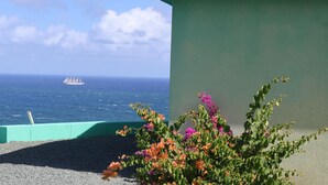 A building with a view of the ocean and a ship in the distance. - Jasdip, Aquatic Serenity where you can reset, relax, be free and breathe! (Cap Estate)