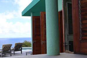 A wooden door with a textured surface, a wooden column, and a view of the ocean.