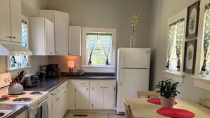 A kitchen with white cabinets, a stove, a refrigerator, and a dining table with chairs.