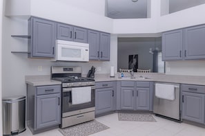 A modern kitchen with grey cabinets, a stainless steel stove, and a microwave. - Wesley Chapel Home 3Bed/2Bath with water view (Zephyrhills)