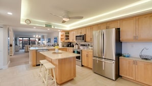 Une cuisine moderne avec des meubles en bois, des appareils en acier inoxydable et un îlot central doté de tabourets.
