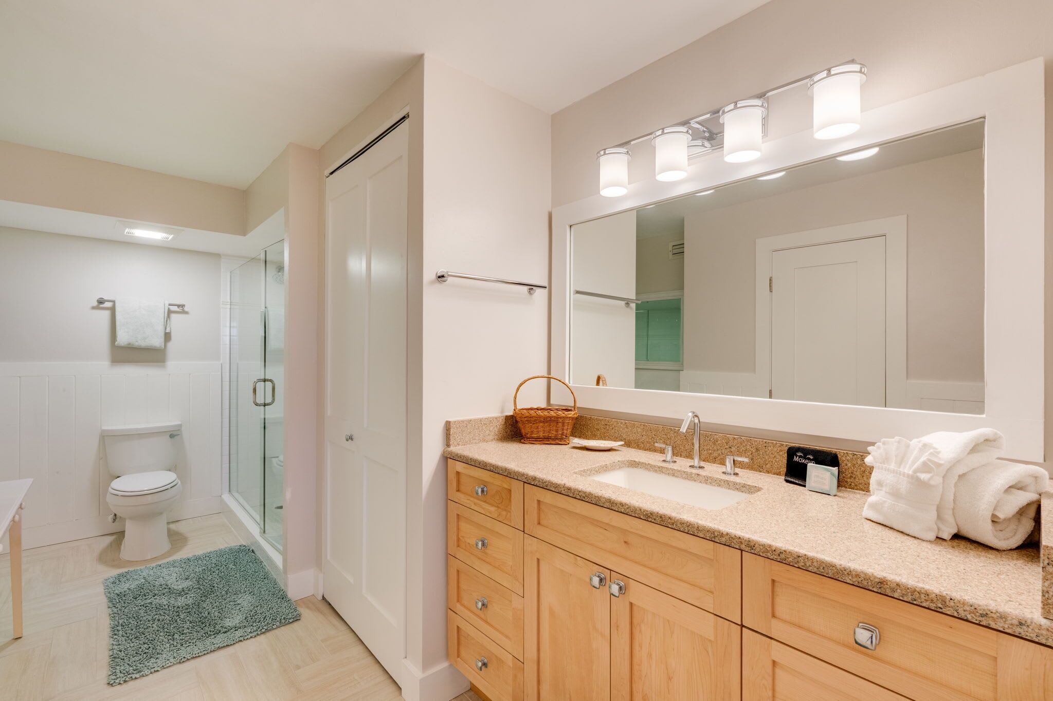 Un baño con cabina de ducha de vidrio, un lavabo con tocador y un espejo grande.