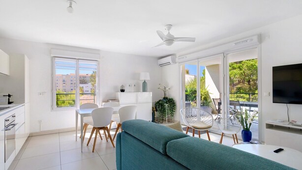 A modern apartment with a kitchen, dining area, and balcony. - Cap Sud, Antibes – Quiet 2-Bedroom, Pool, Parking (Antibes)