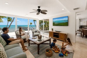 A spacious living room with a large TV, a ceiling fan, and a view of the ocean. - Southwind Private Beachfront Estate with Infinity Pool, Spa and Fishing Pier (Islamorada)