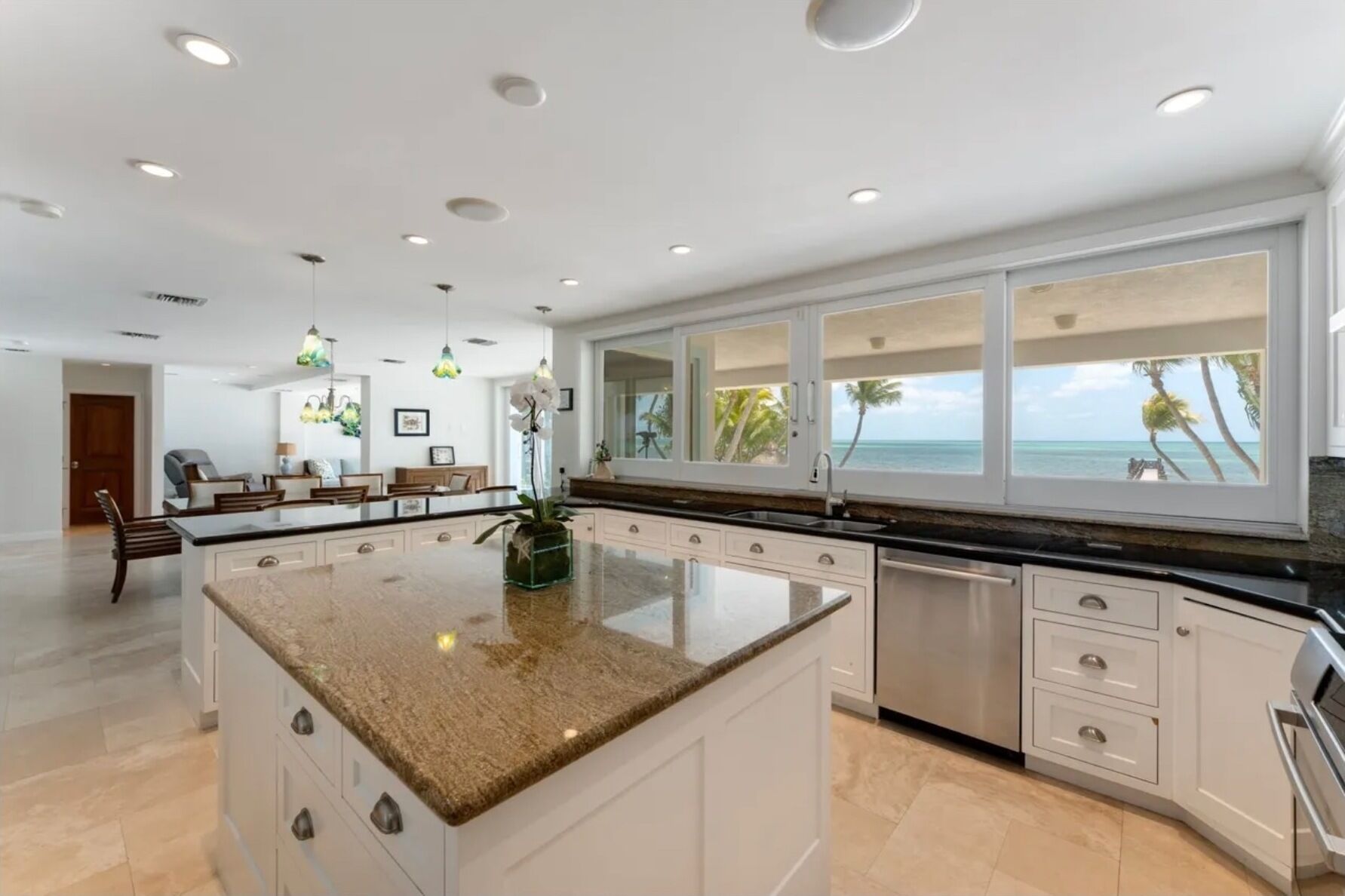A spacious kitchen with a large island, white cabinetry, and a view of the ocean.