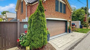 Ein zweistöckiges Backsteinhhaus mit Garage, einem gepflegten Rasen und einer hohen Nadelbaum.'