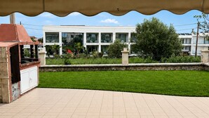 Área de varanda coberta com churrasqueira e vista para um edifício com várias janelas.