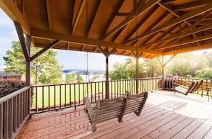 A wooden deck with a swing, a railing, and a view of a green landscape. - Family Friendly 3BR/3BA w/ Pools, Pickleball, Putt Putt and Much More! (Hot Springs)