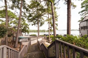 Un escalier en bois mène à une terrasse d’où l’on peut admirer un lac, le tout étant entouré de grands arbres.