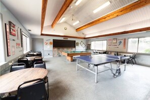 A room with a ping pong table, pool table, and billiards table. There are chairs and tables arranged for dining. - Family Friendly 3BR/3BA w/ Pools, Pickleball, Putt Putt and Much More! (Hot Springs)