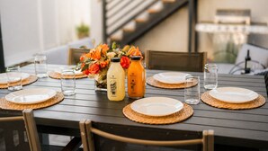 Una mesa de comedor dispuesta con platos, vasos y dos botellas de jugo de naranja.