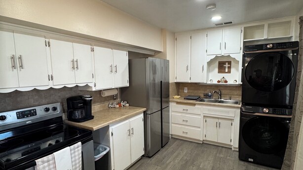 A modern kitchen with stainless steel appliances, white cabinetry, and a wooden floor.