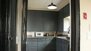 A kitchen with dark cabinets, a microwave, and a sink. - Coastal Farmhouse near Basin Head and Red Point (Lot 46)