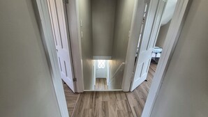 A narrow hallway with wooden flooring and white walls. - Coastal Farmhouse near Basin Head and Red Point (Lot 46)