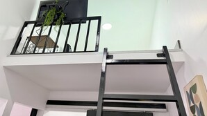 Ein mehrstöckiger Innenraum mit Treppe, einer an der Decke befestigten Fernseher und einer Pflanze.