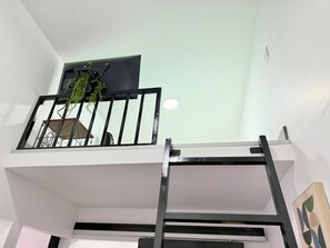 Ein mehrstöckiger Innenraum mit Treppe, einer an der Decke befestigten Fernseher und einer Pflanze.