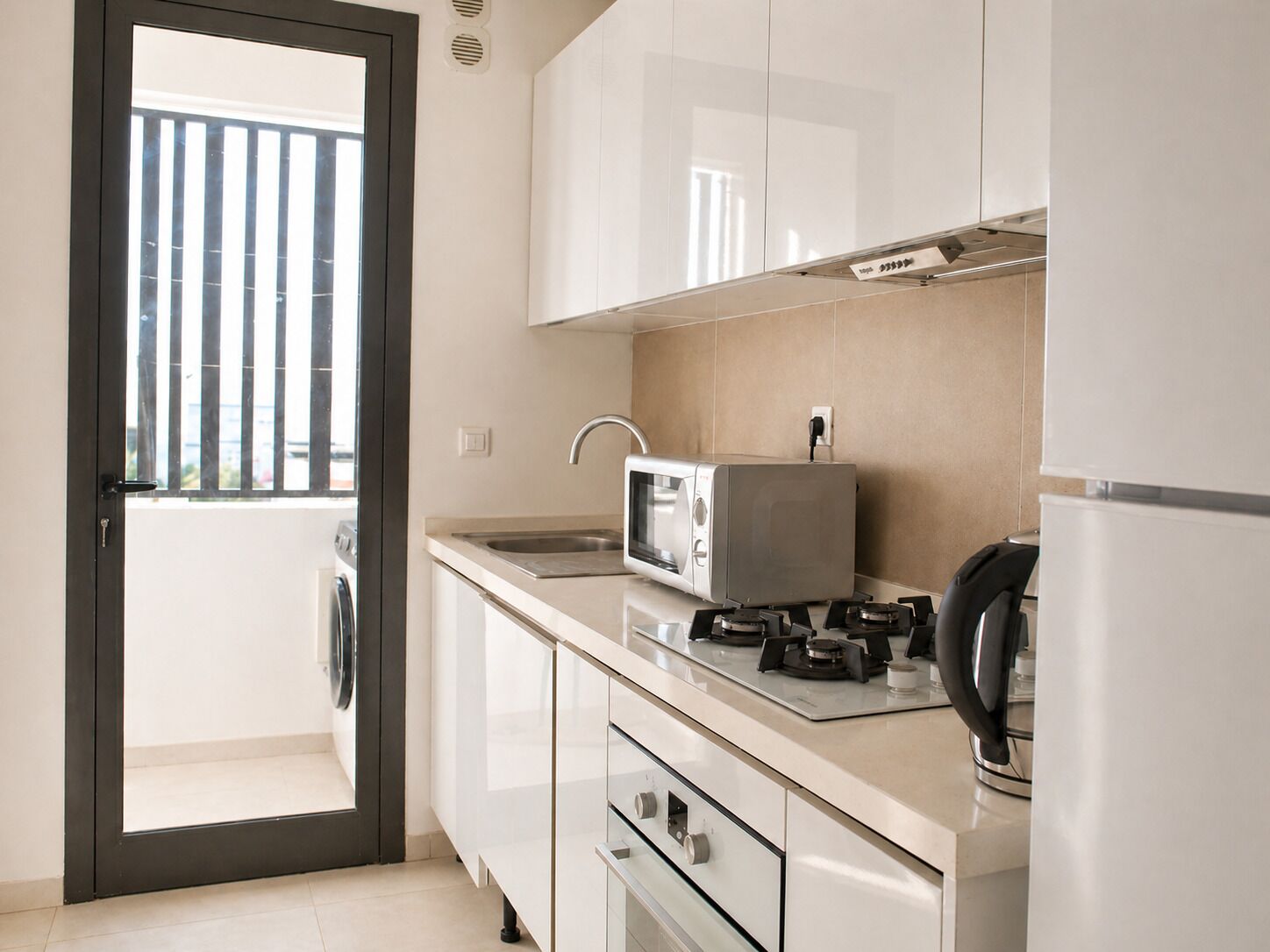 A modern kitchen with a microwave, stove, sink, and a refrigerator.