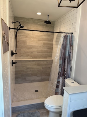 Une salle de bain moderne équipée d’une douche, de toilettes et d’un porte-serviettes.