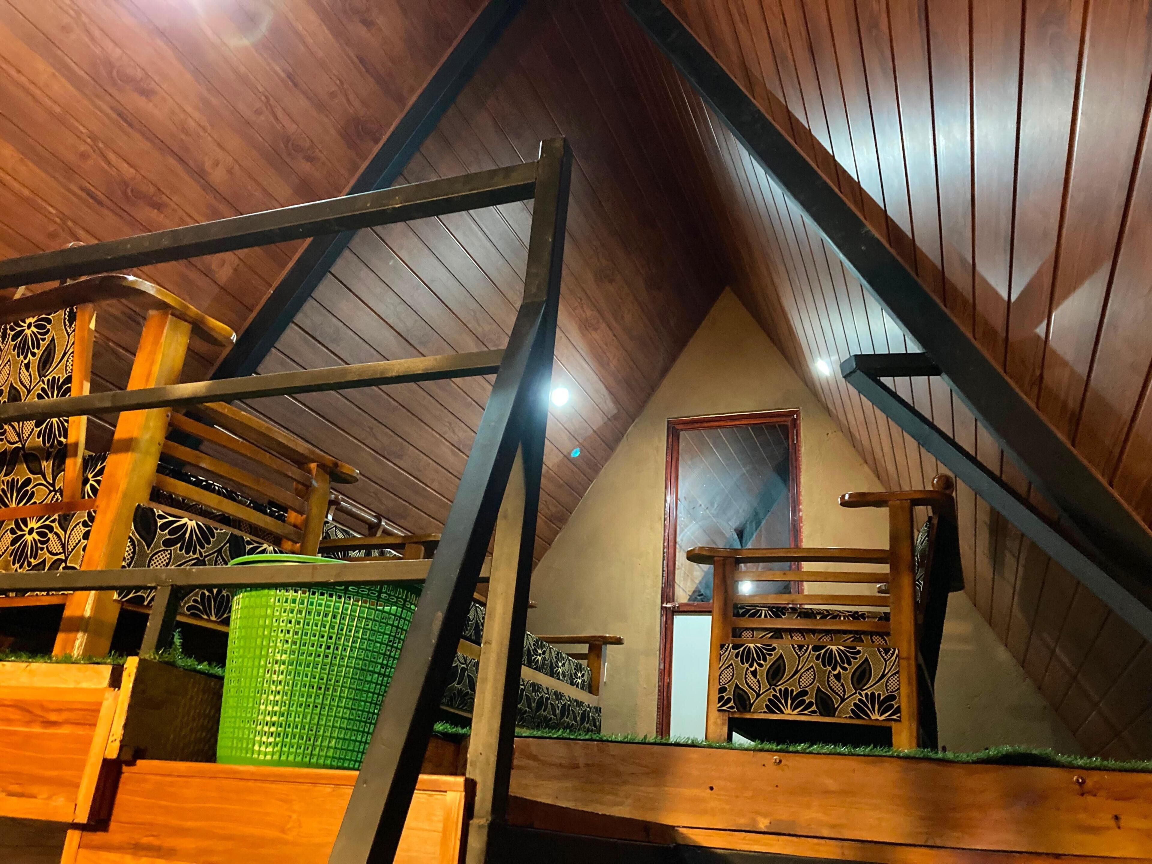 Una escalera de madera con barandilla de metal que lleva a una zona elevada con ventana.