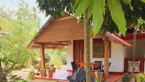 Una casa con porche cubierto, plantas en macetas y mobiliario exterior.