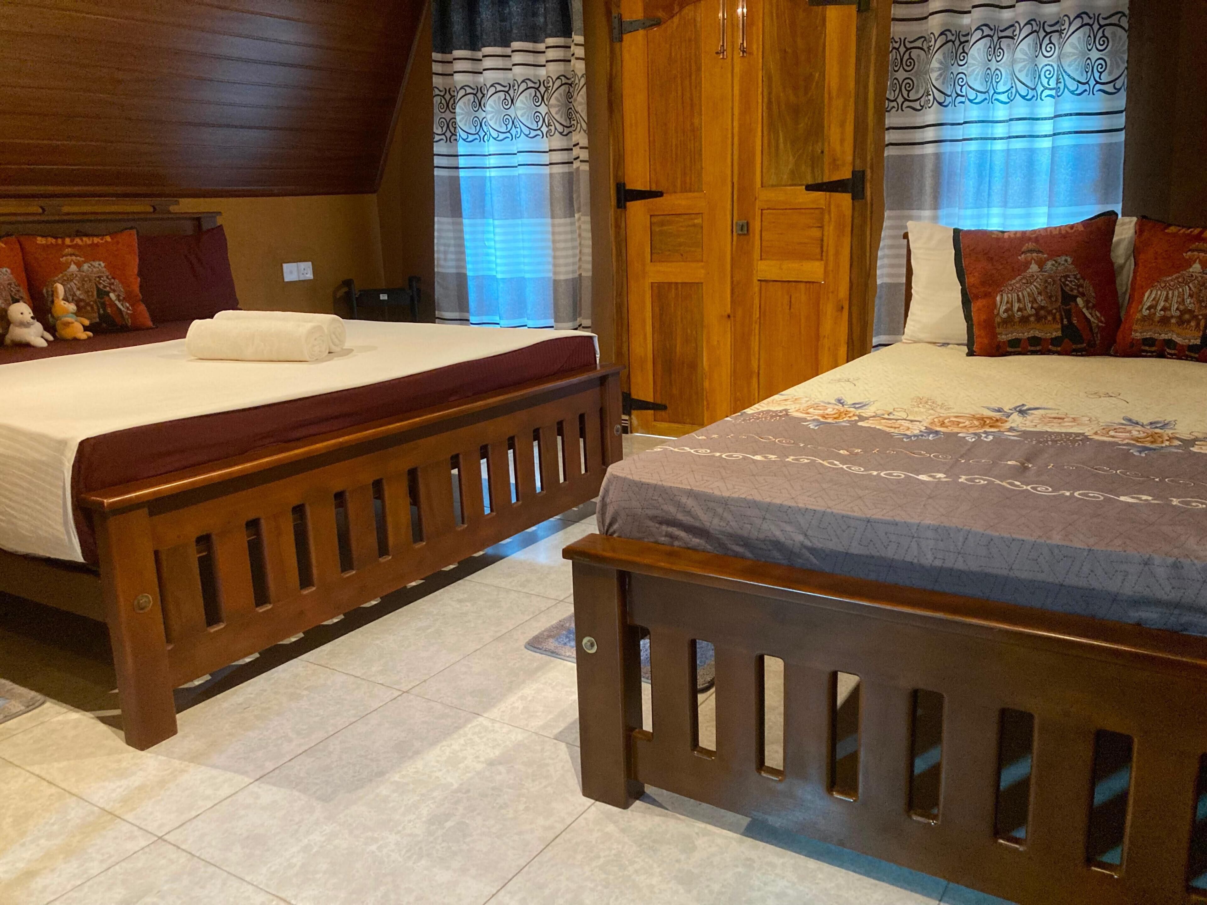 A bedroom with two wooden beds, a wardrobe, and a window with curtains.