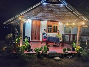 Una casa con un porche cubierto, una mesa de comedor y plantas en macetas.