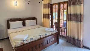 Un dormitorio con cama de madera, una ventana con cortinas, un aire acondicionado instalado en la pared y una alfombra estampada.