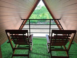 Una habitación con dos sillas de madera orientadas hacia una ventana que da a zonas verdes.