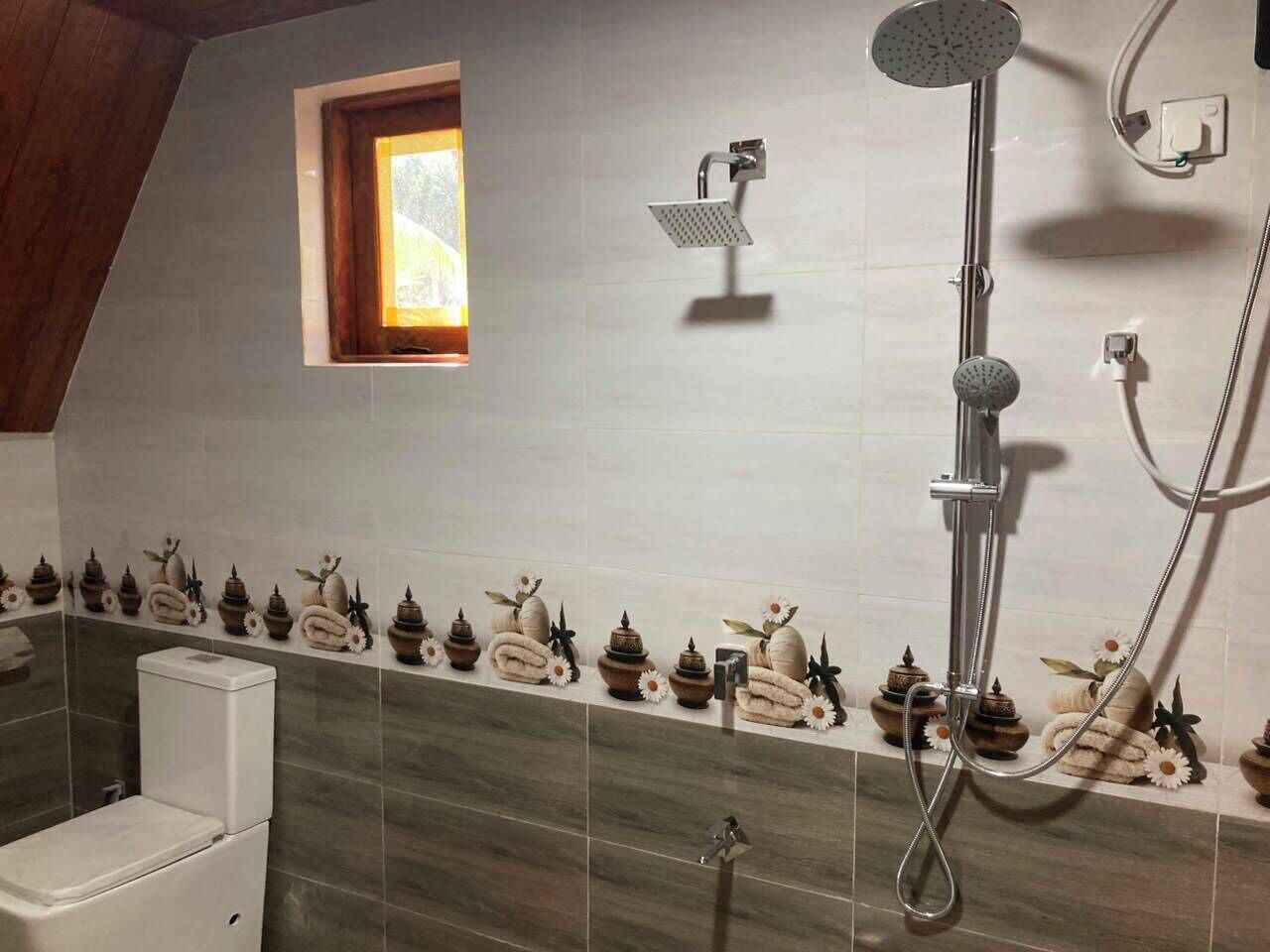 A bathroom with a shower, a toilet, and a window.