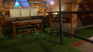 Un interior con techo triangular, asientos estampados y una mesa de madera.
