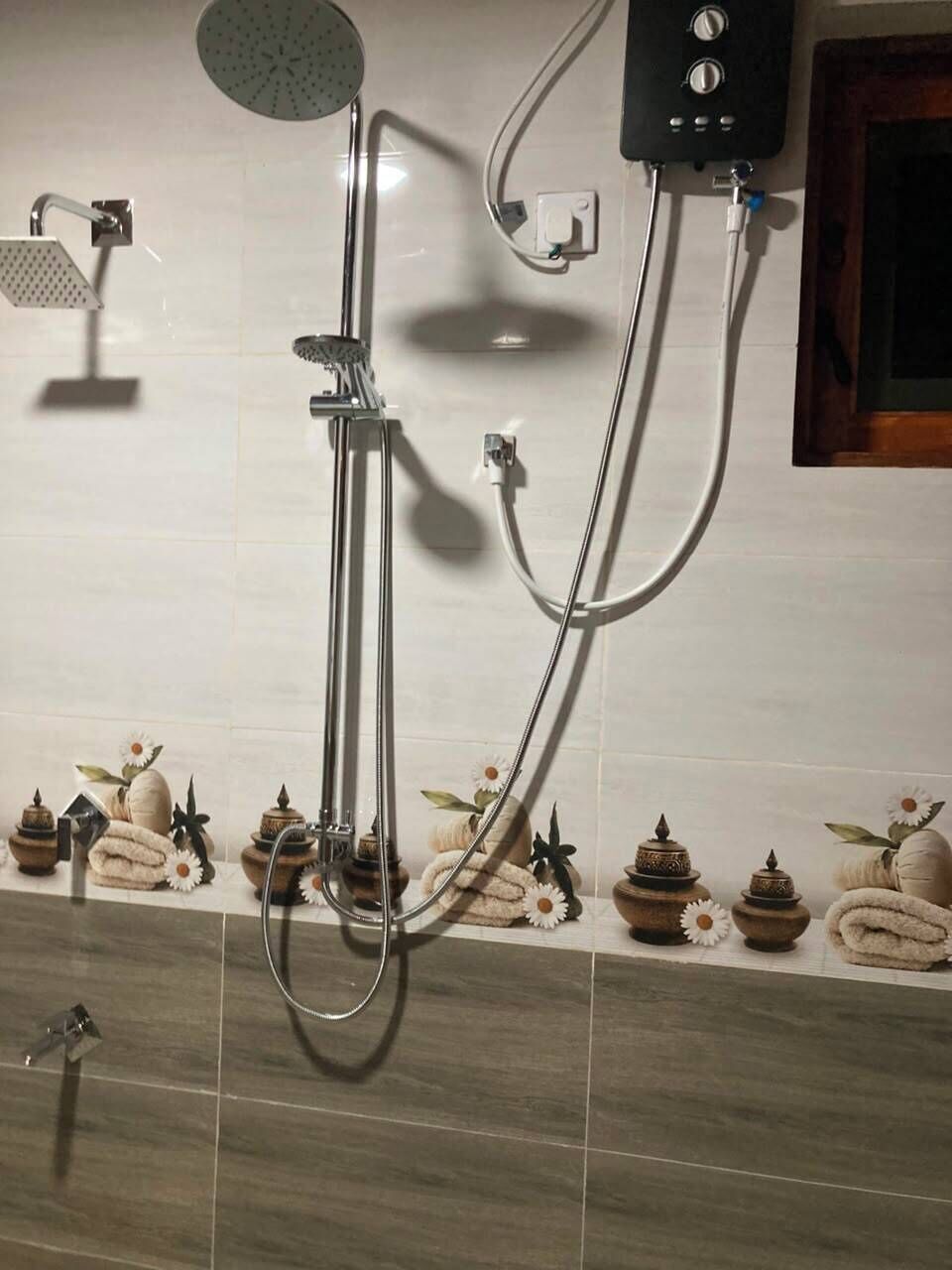 Un baño con ducha, toallero y calentador de pared.