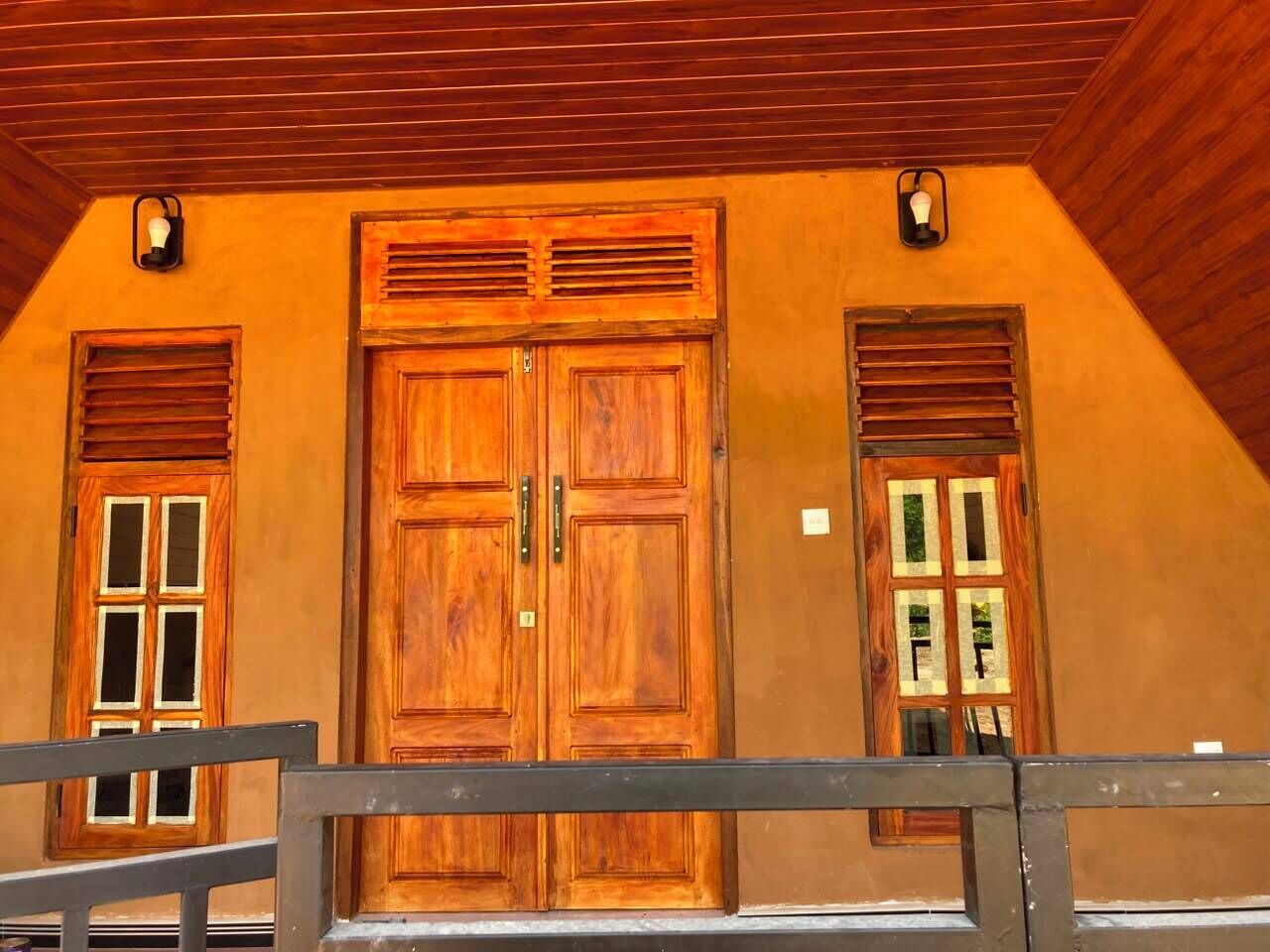 A building with a wooden facade, large double doors, and two windows with shutters.