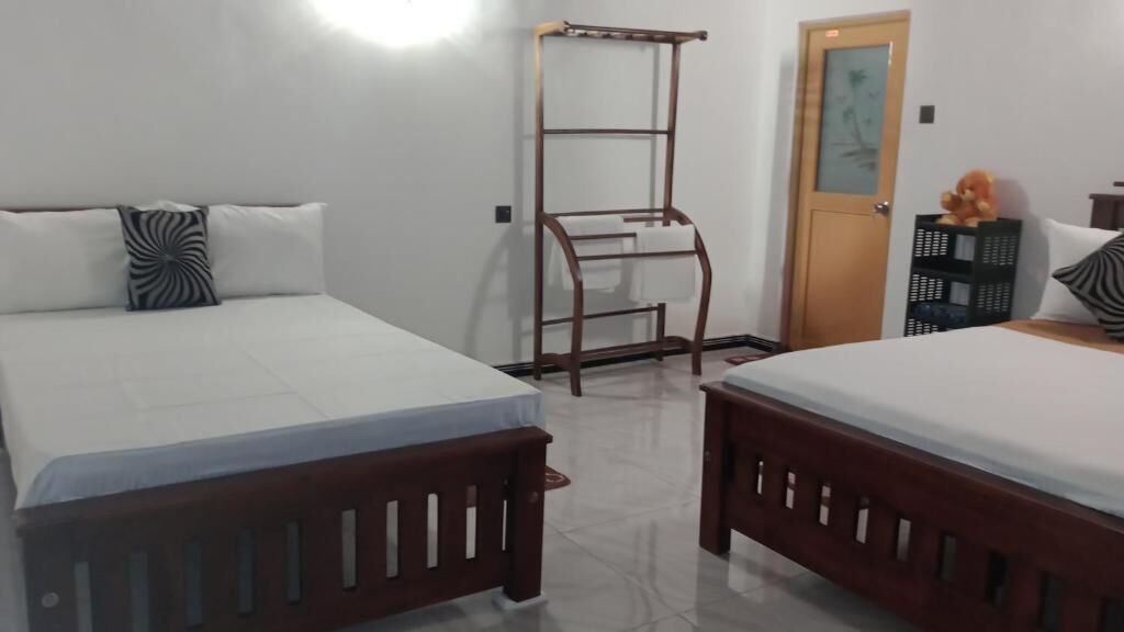 A room with two beds, a wooden ladder, a door with a glass panel, and a small table with a stuffed toy.