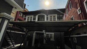 Un edificio con un porche techado, una escalera y cielo despejado.